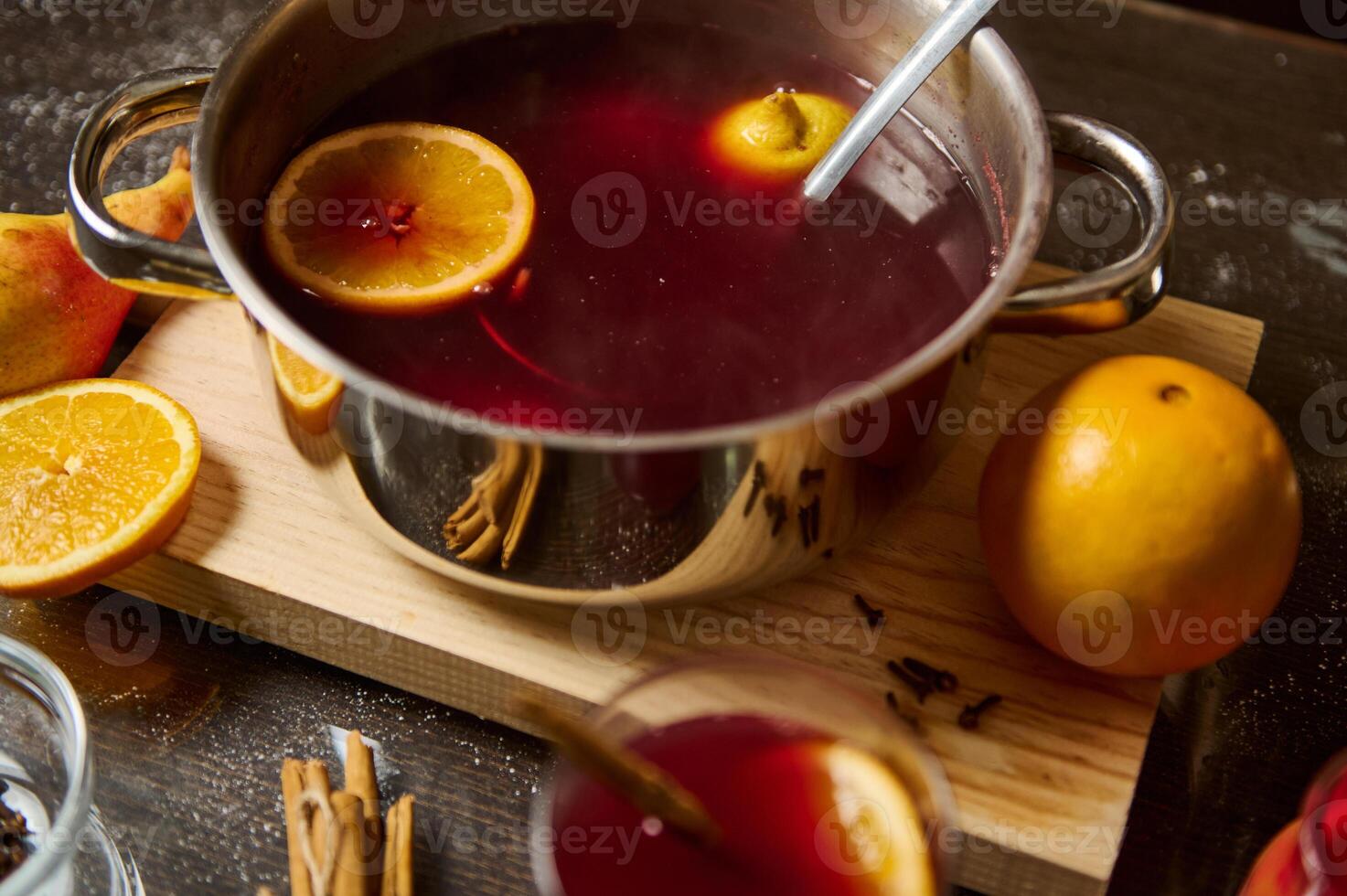 Warm mulled wine with oranges and spices on wooden board photo