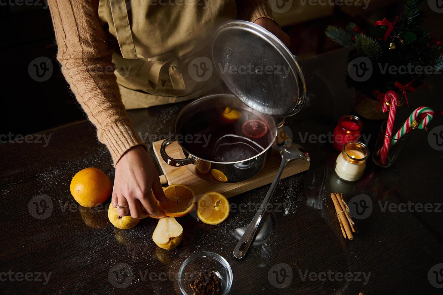 Person preparing mulled wine with fresh fruits and spices on the table photo