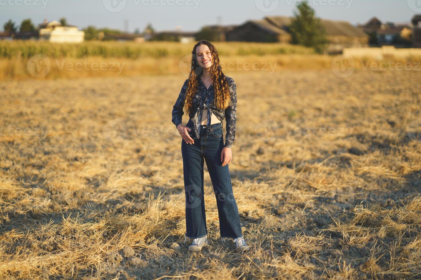 A Young Woman is Gracefully Posing in a Sunlit Field While Wearing a Charming Vintage Style Outfit photo