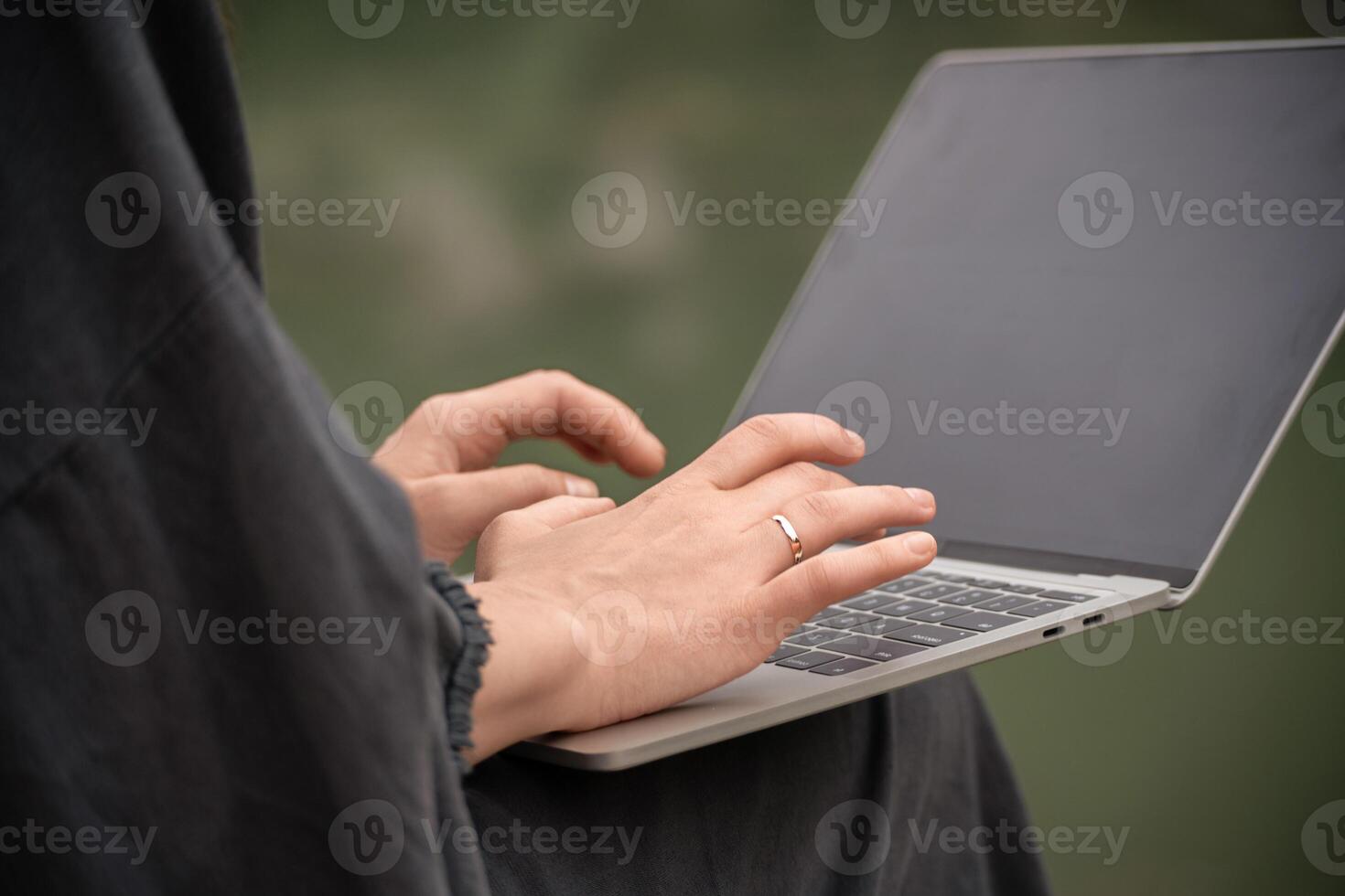 A woman is typing on a laptop with a ring on her finger. Concept of productivity and focus, as the woman is engaged in a task on her computer. photo