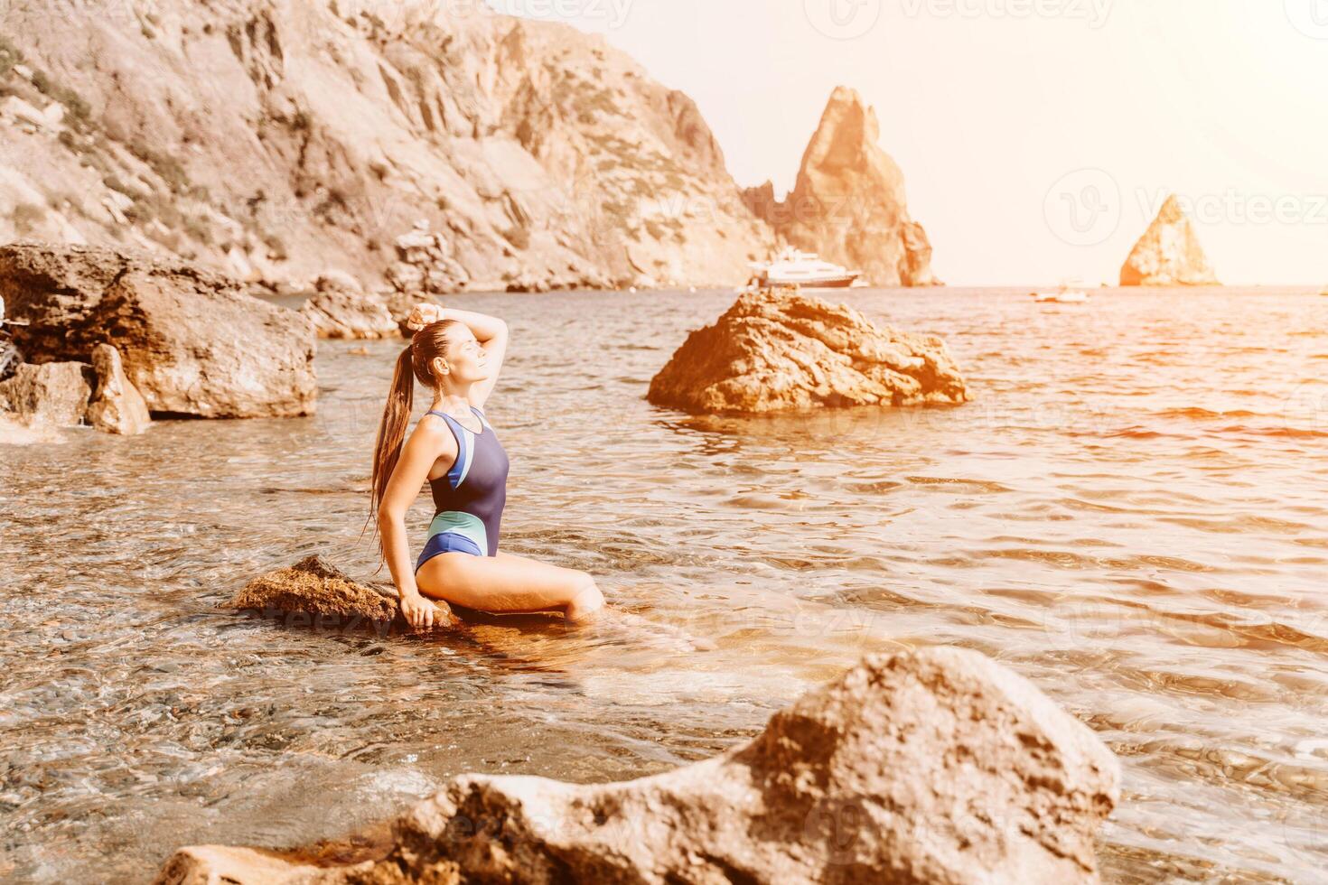 Woman travel summer sea. A happy tourist in a blue bikini enjoying the scenic view of the sea and volcanic mountains while taking pictures to capture the memories of her travel adventure. photo