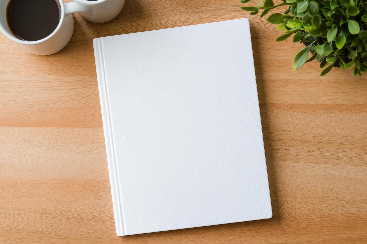 Blank notebook positioned between two coffee cups with plants on a wooden table photo