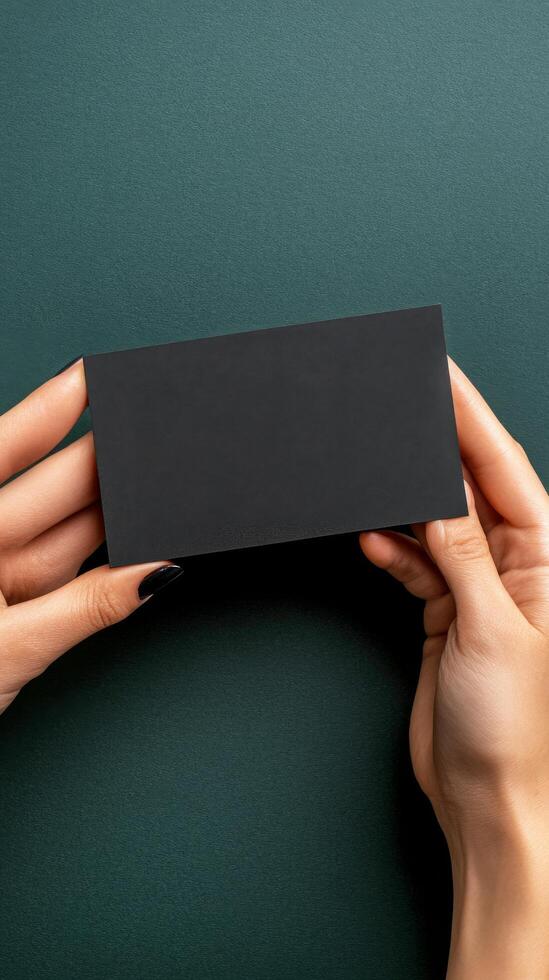 Hand holding a black card against a dark green background in a contemporary setting photo
