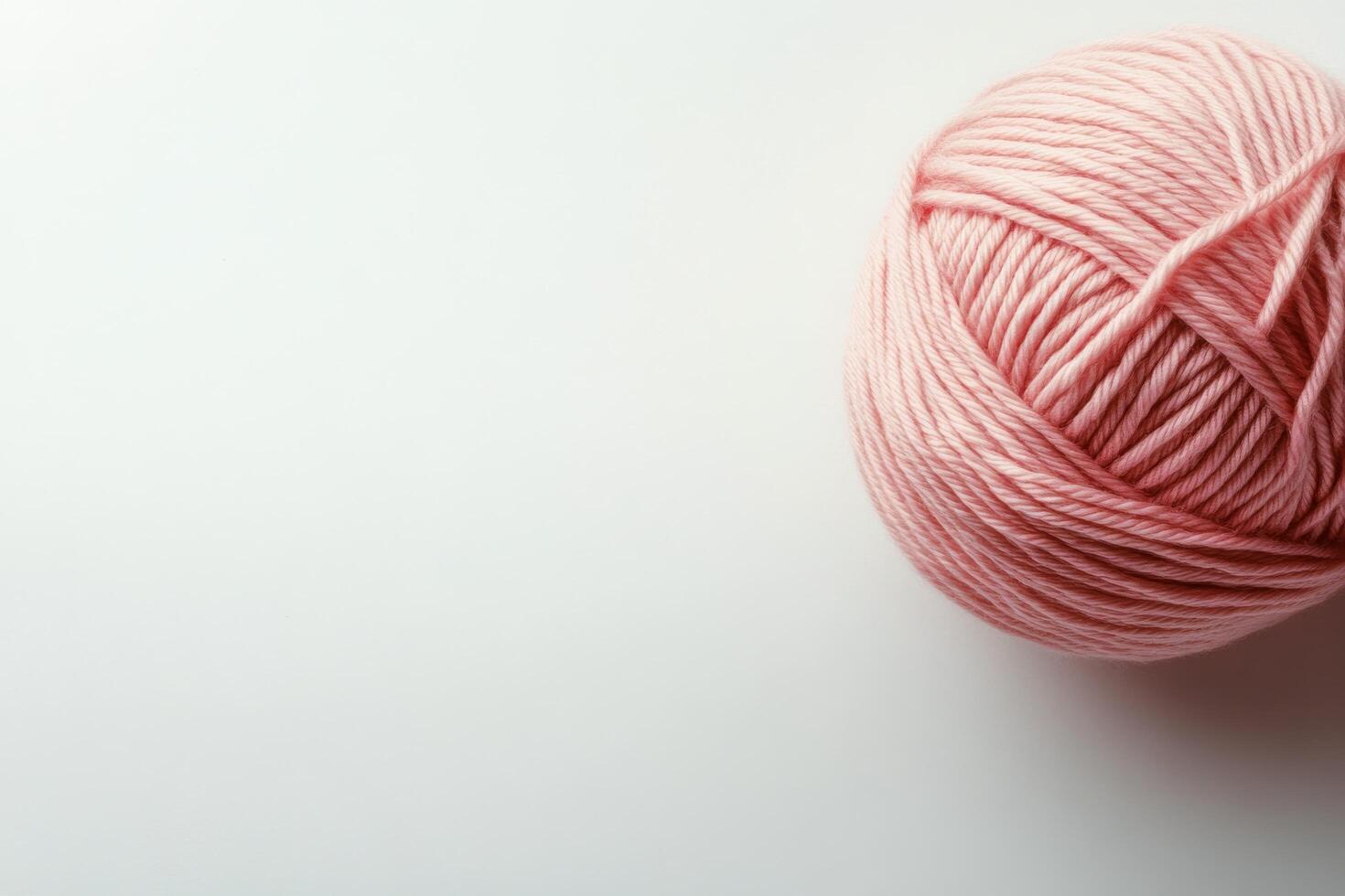 Soft pink yarn ball resting on a clean white surface in a cozy craft space photo