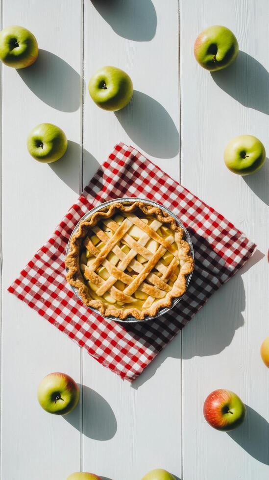 Freshly baked apple pie surrounded by green apples on a checkered cloth photo