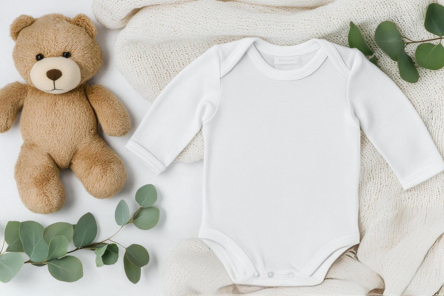 Cute baby outfit and bear arranged on a soft blanket with greenery accents photo
