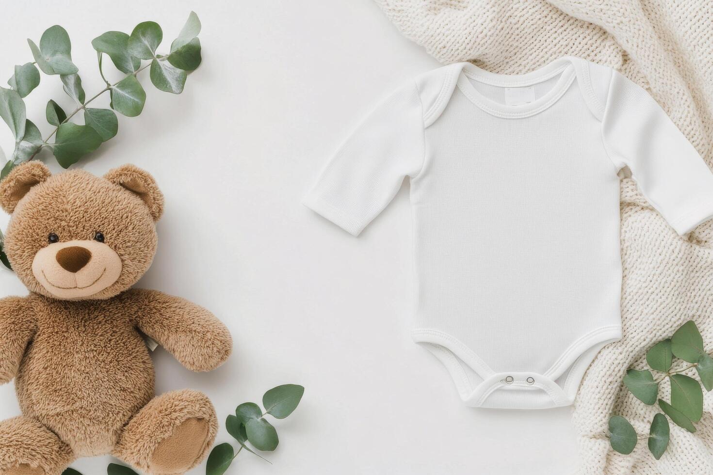 Cute baby outfit and bear arranged on a soft blanket with greenery accents photo