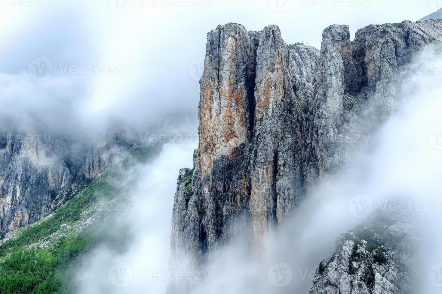 A mountain with tall rock formations in the clouds photo