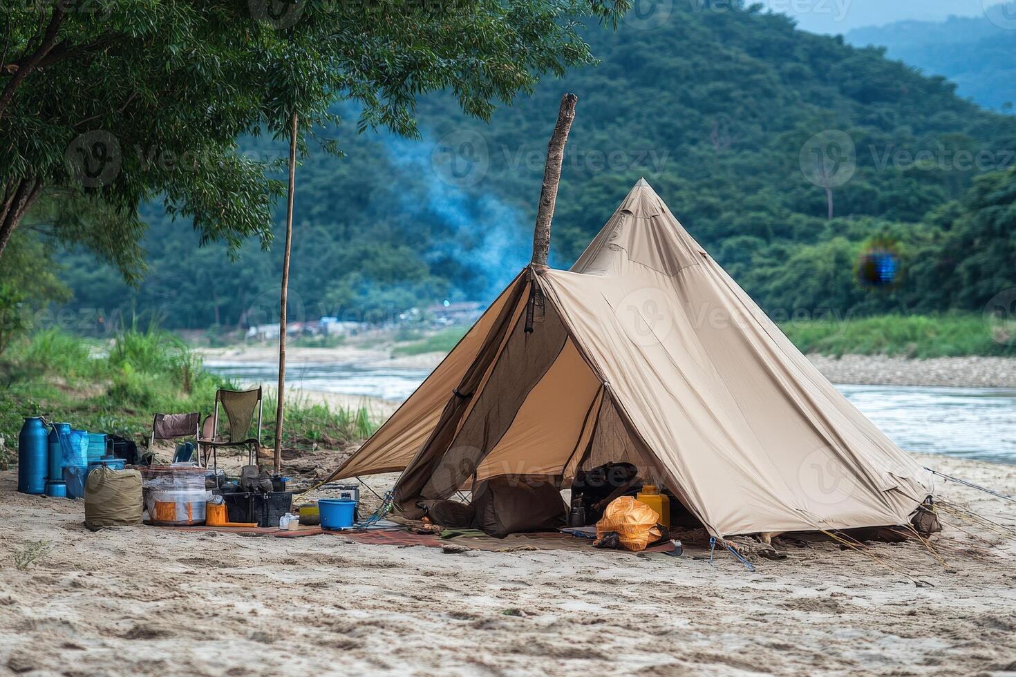 A tent set up on the beach with a river in the background photo