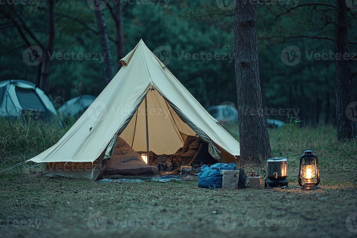 A tent in the woods with a lantern and a lamp photo