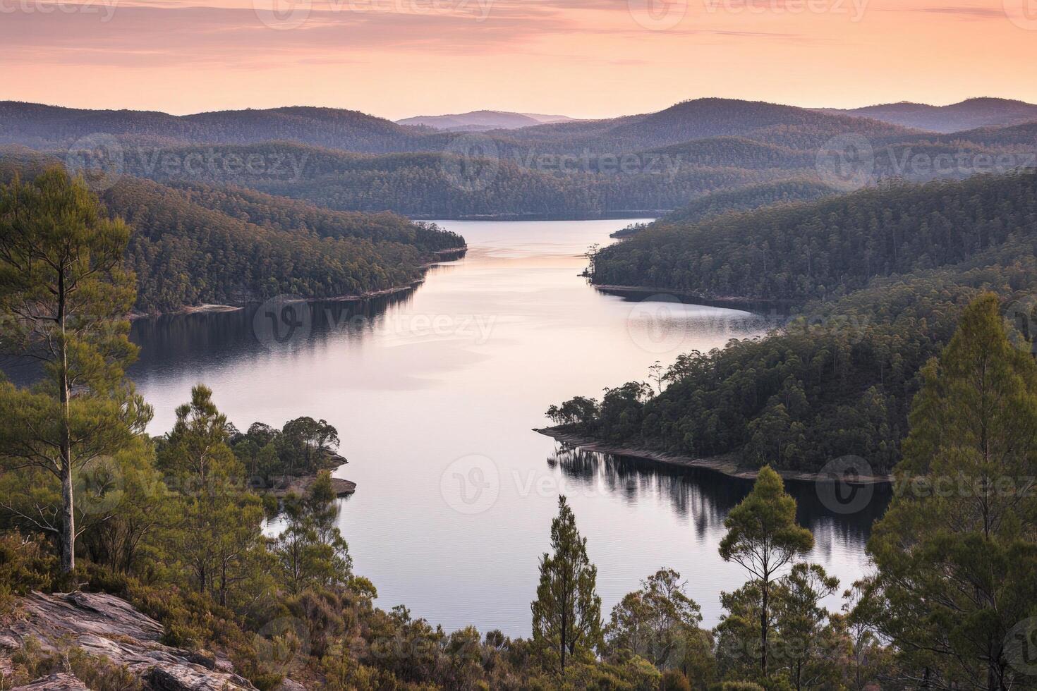 A lake surrounded by trees and hills at sunset photo