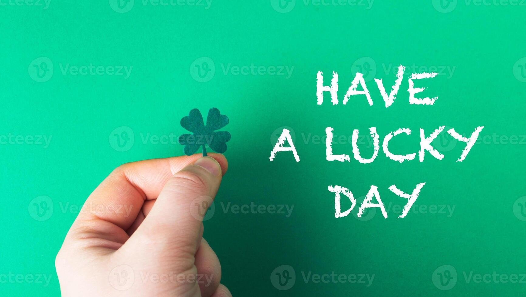 A hand holding a shamrock and the words have a lucky day written below it photo