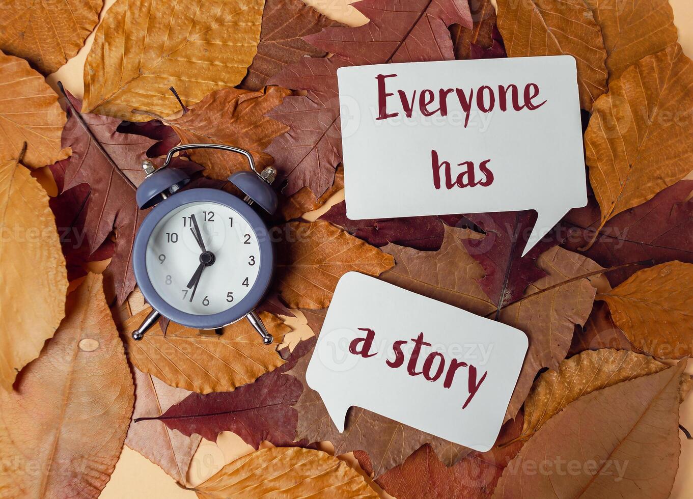 Clock and two speech bubbles on a pile of leaves photo