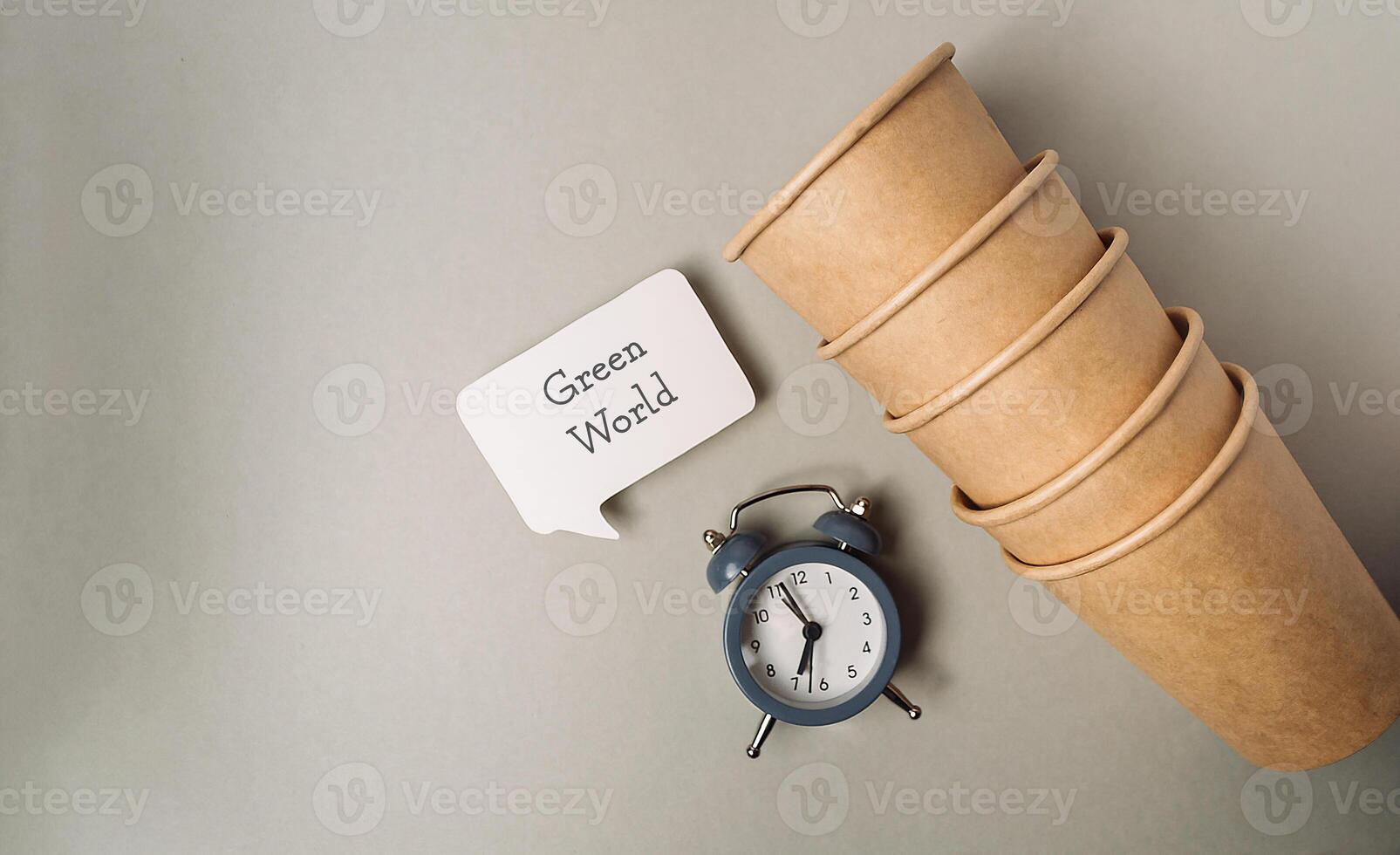 Clock sits on a table next to a stack of paper cups photo