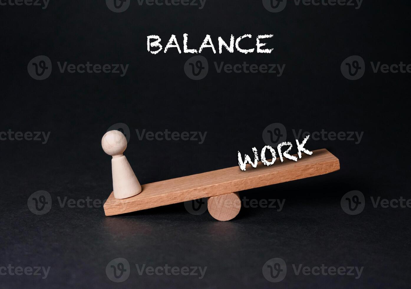 Wooden scale with a person on one side and the word balance on the other photo