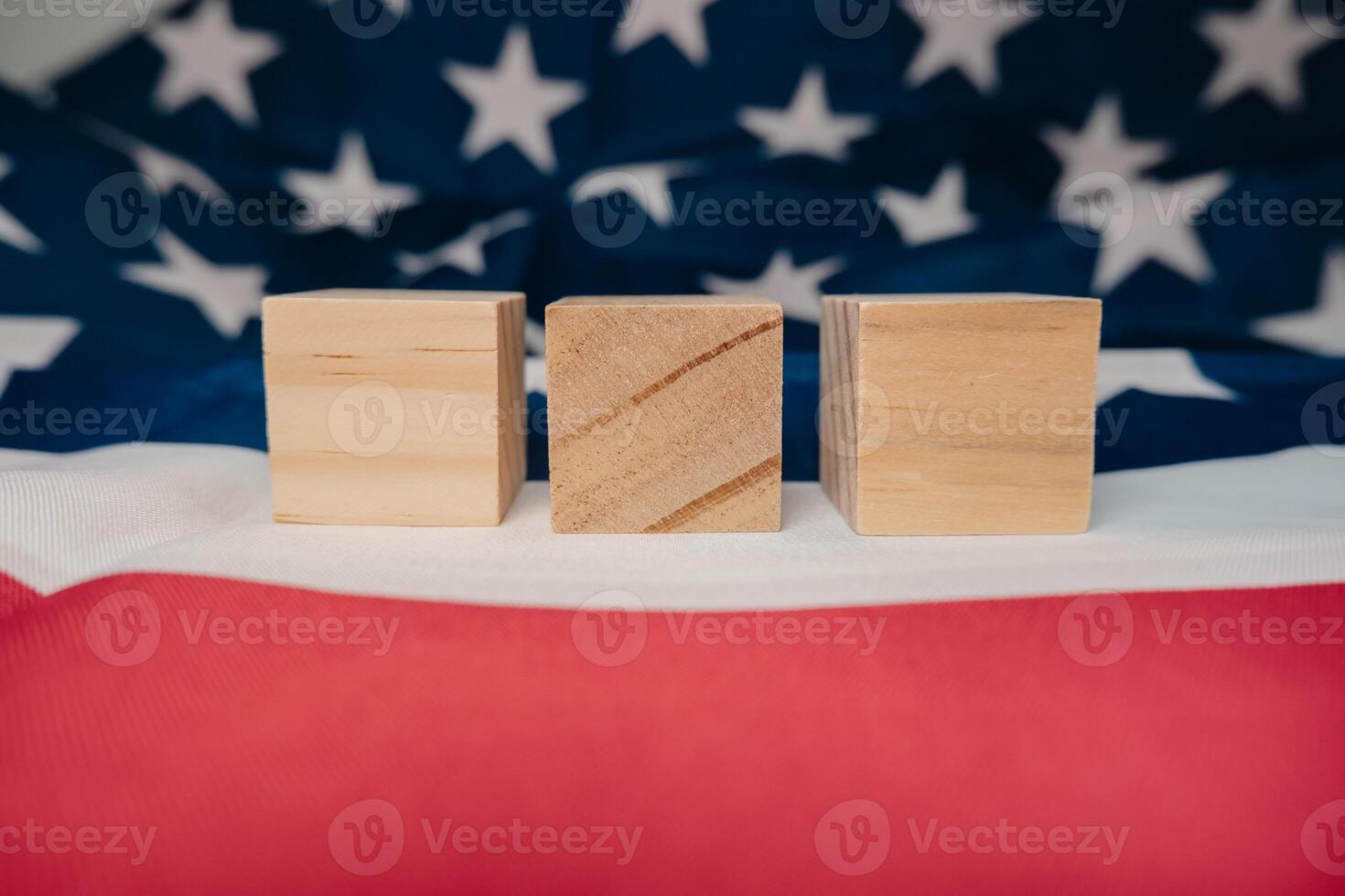 Three wooden blocks are placed on top of a red and white American flag photo