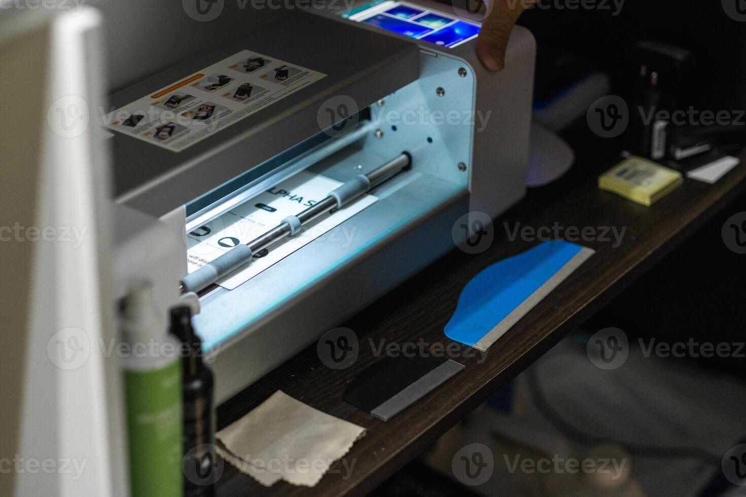 Operator uses a precise cutting plotter for hydrogel film preparation in a workshop setting during daylight hours photo