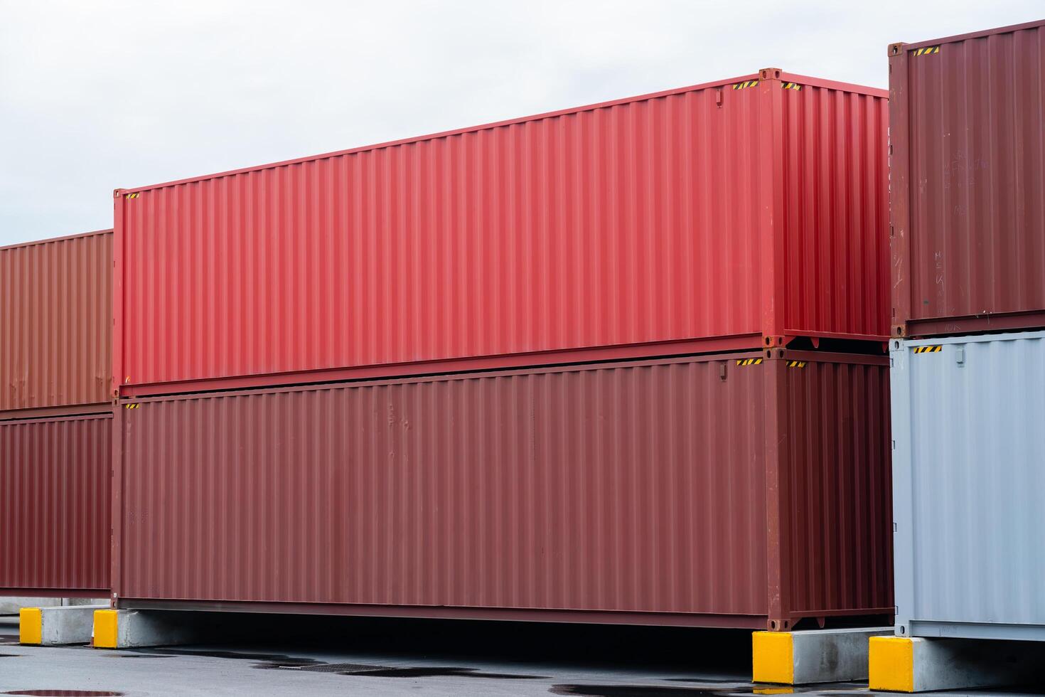 A pile of shipping containers, some of which are red and some are brown. The red containers are stacked on top of the brown containers, creating a visually interesting and dynamic scene photo