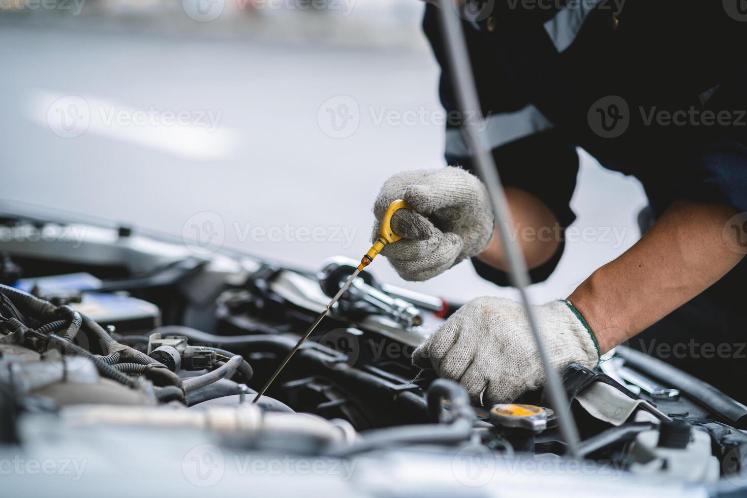 A mechanic is working on a car engine, checking the oil level and adding more if necessary. Concept of responsibility and attention to detail photo