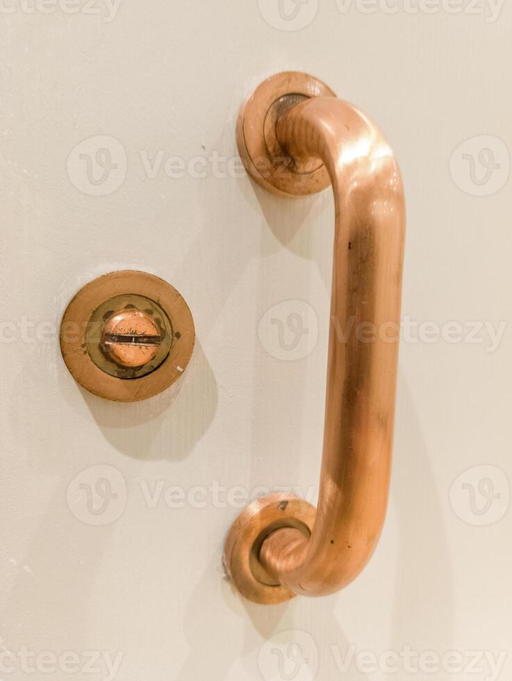 A close up of a copper handle on a white door photo