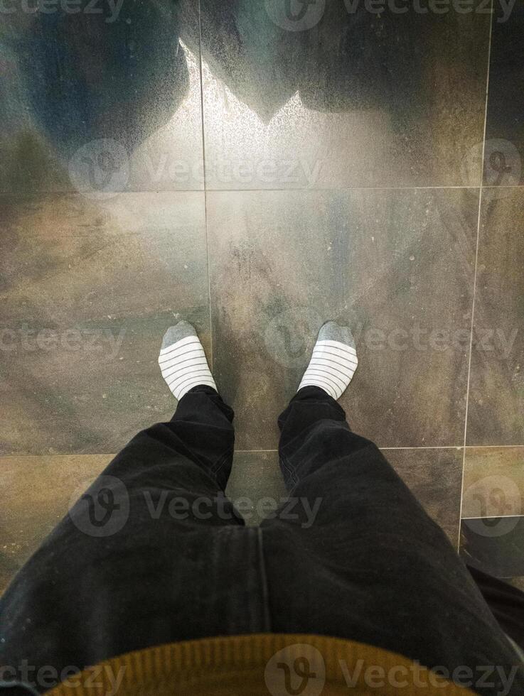 A person standing on a tiled floor with their feet in socks photo