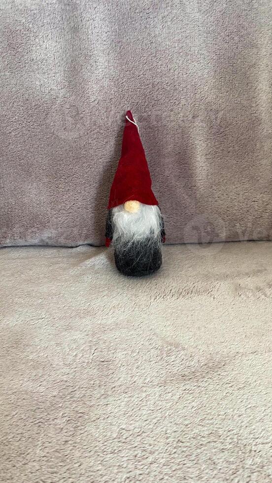 A small gnome with a red hat sitting on a couch photo
