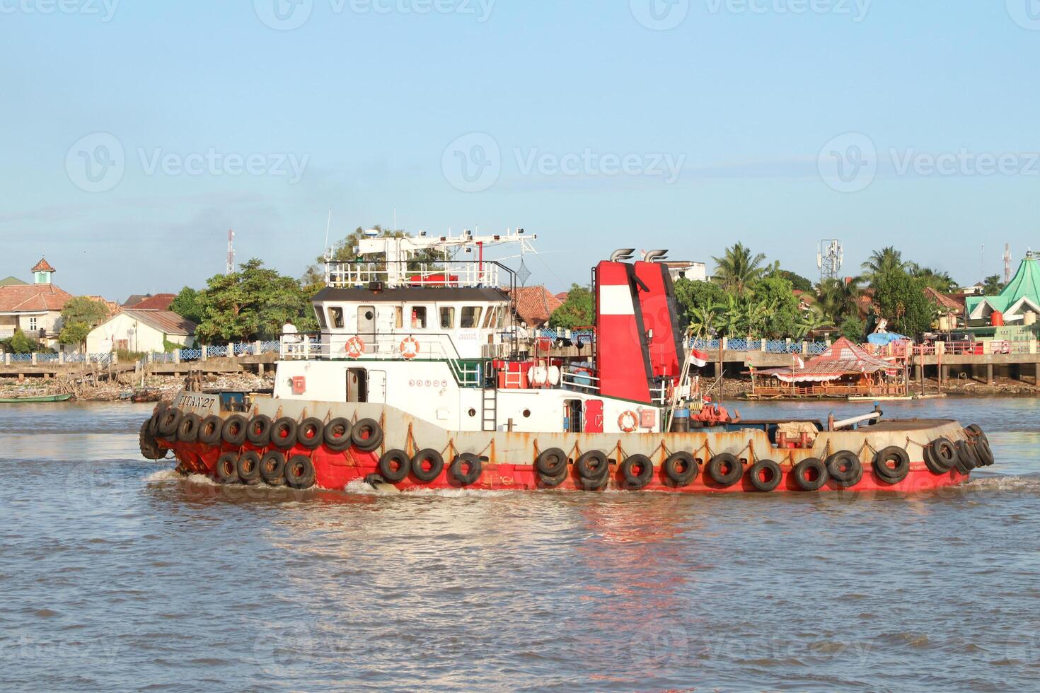 tugboat pulling a heavily laden coal barge sailing on the Musi River. photo