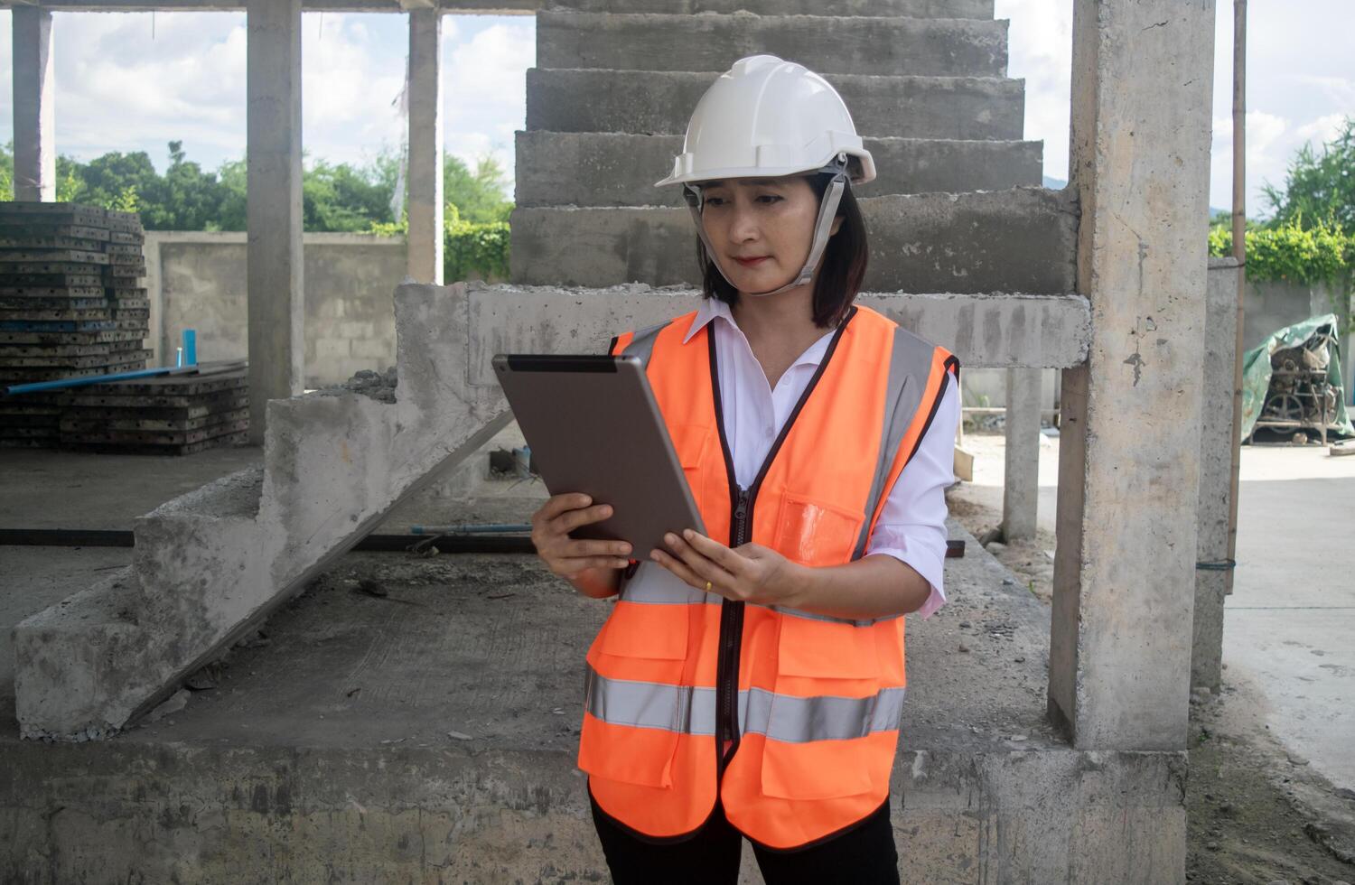 Engineer civil woman wearing uniform safety and hardhat holding using tablet working inspector new project building at construction site photo