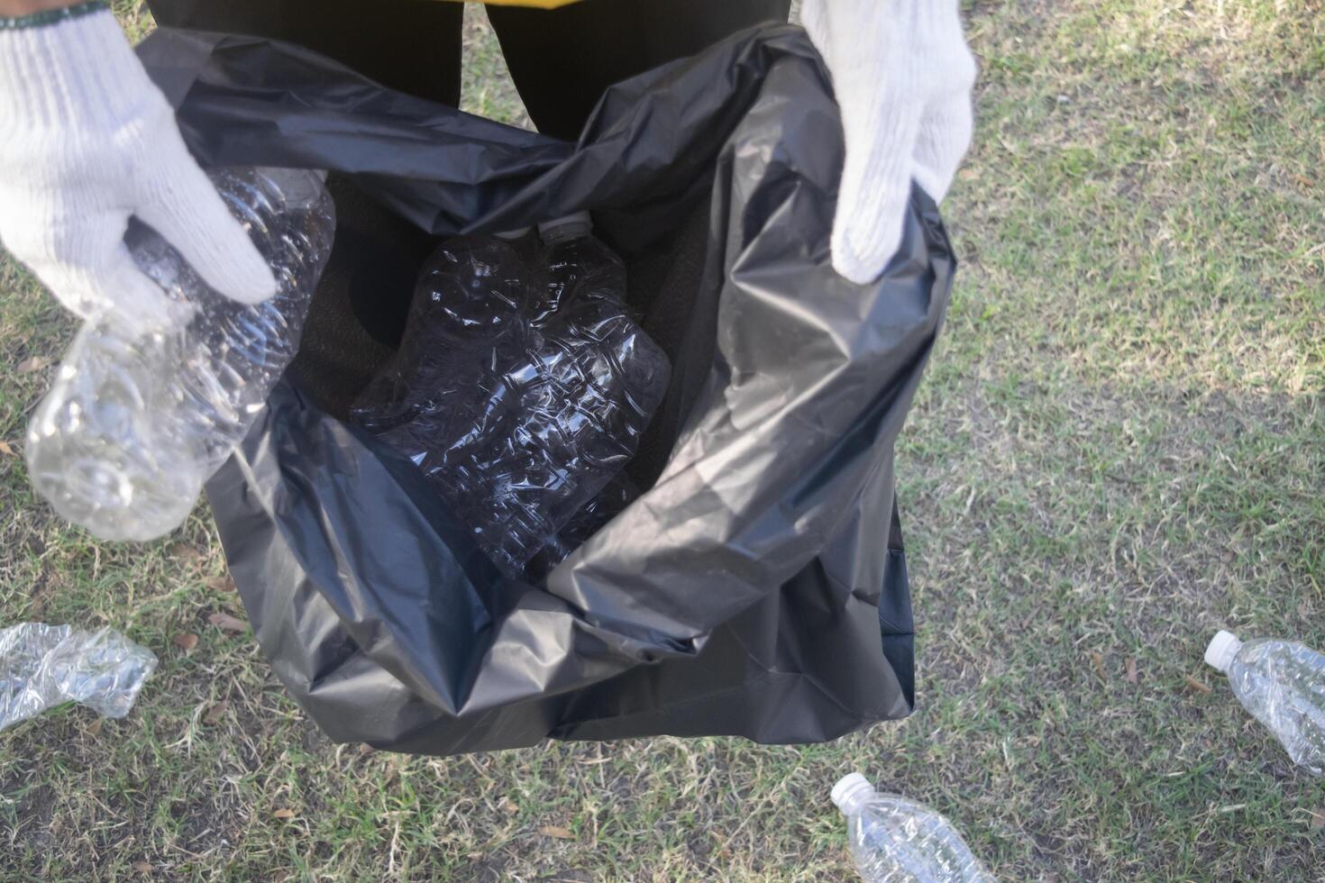 Asian woman picking plastic bottle into trash plastic bag black clean up ecology environmental ecology concept photo