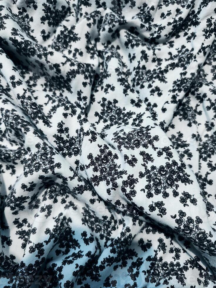 The pattern and background of the fabric is white with a small black flower motif photo