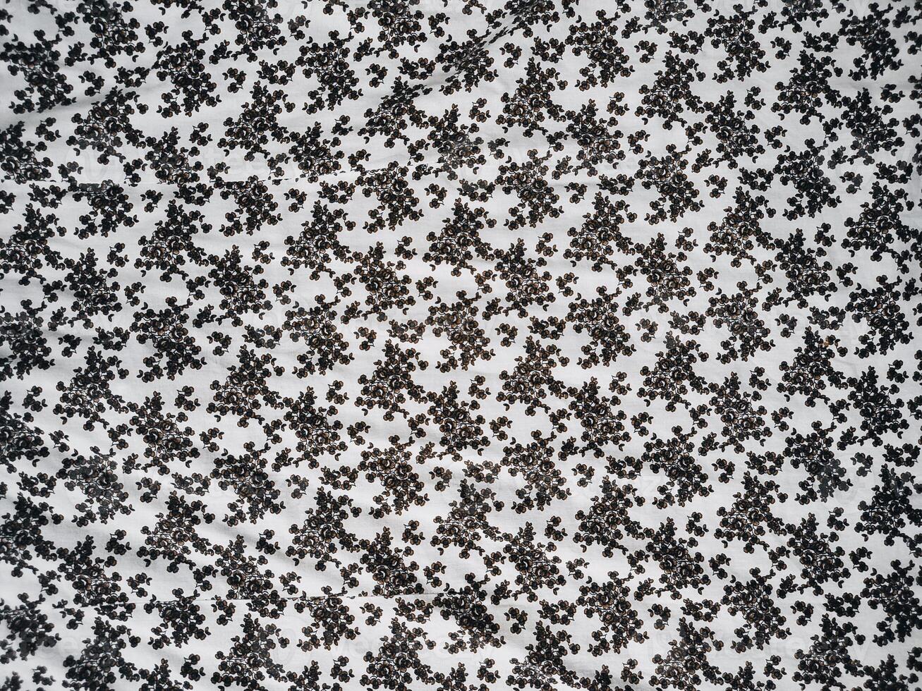 The pattern and background of the fabric is white with a small black flower motif photo