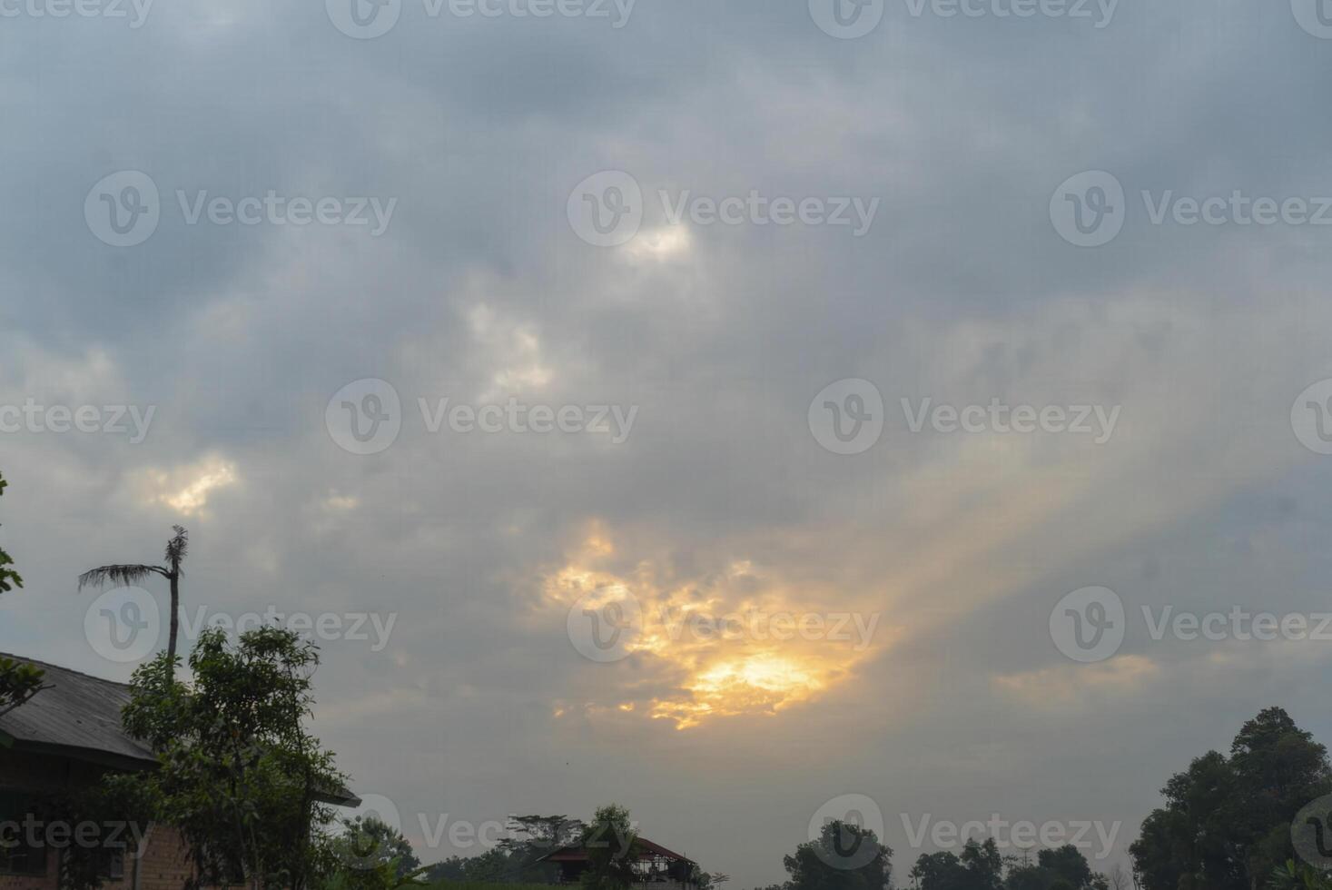 A cloudy sky with a sun shining through photo