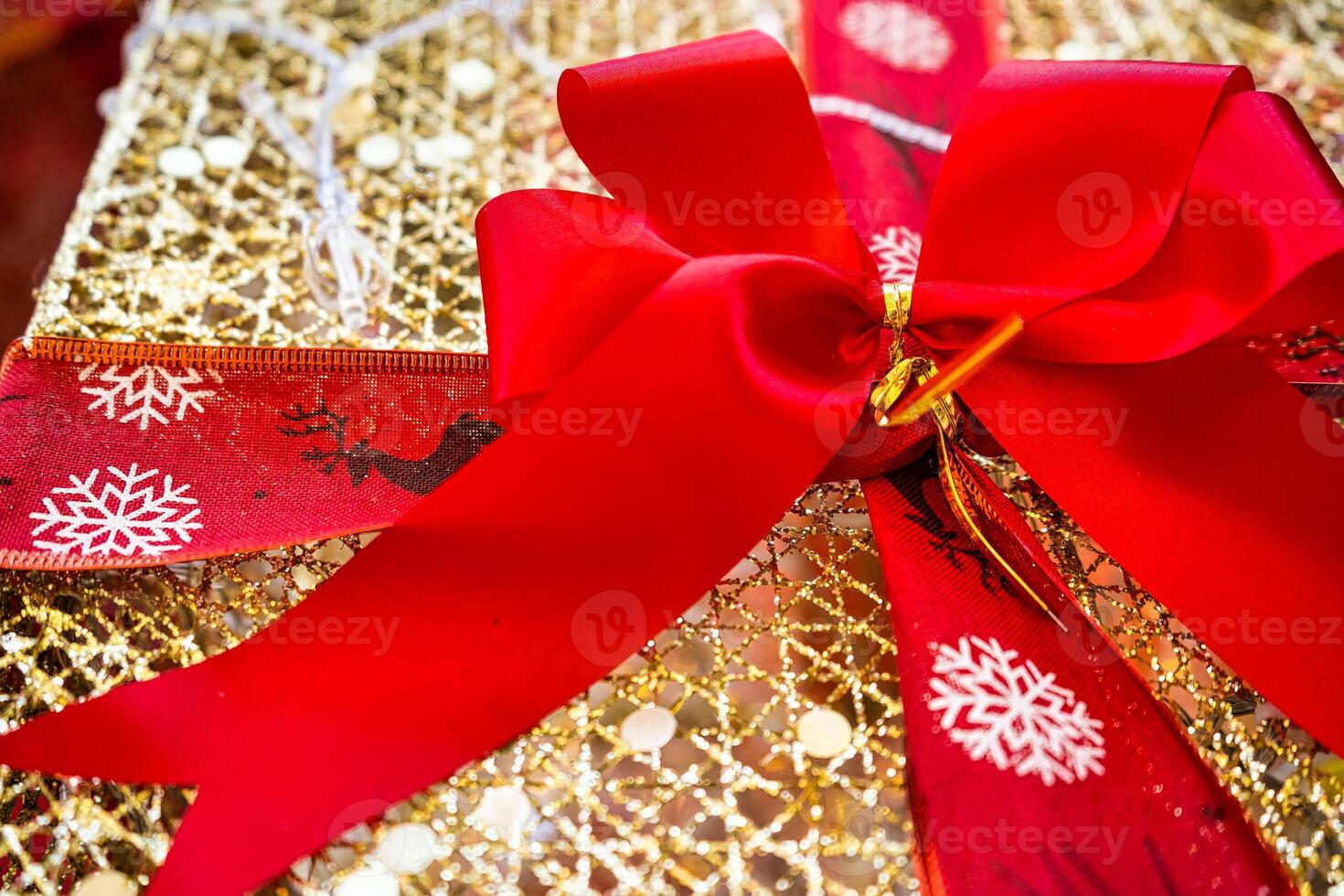 Festive Gift Box Adorned with a Red Ribbon and Gold Wrapping Paper, Radiating Holiday Spirit photo