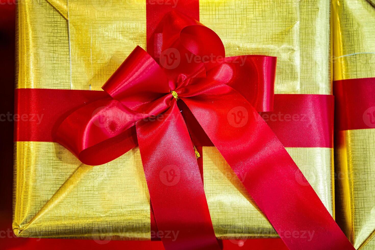 Festive Gift Box Adorned with a Red Ribbon and Gold Wrapping Paper, Radiating Holiday Spirit photo