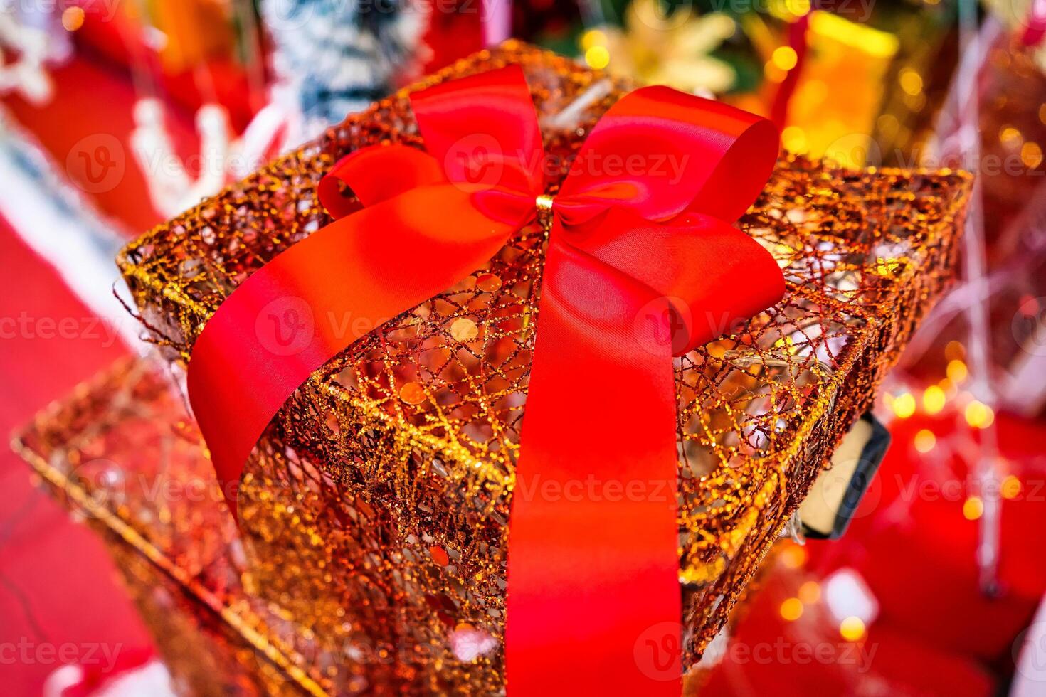 Festive Gift Box Adorned with a Red Ribbon and Gold Wrapping Paper, Radiating Holiday Spirit photo