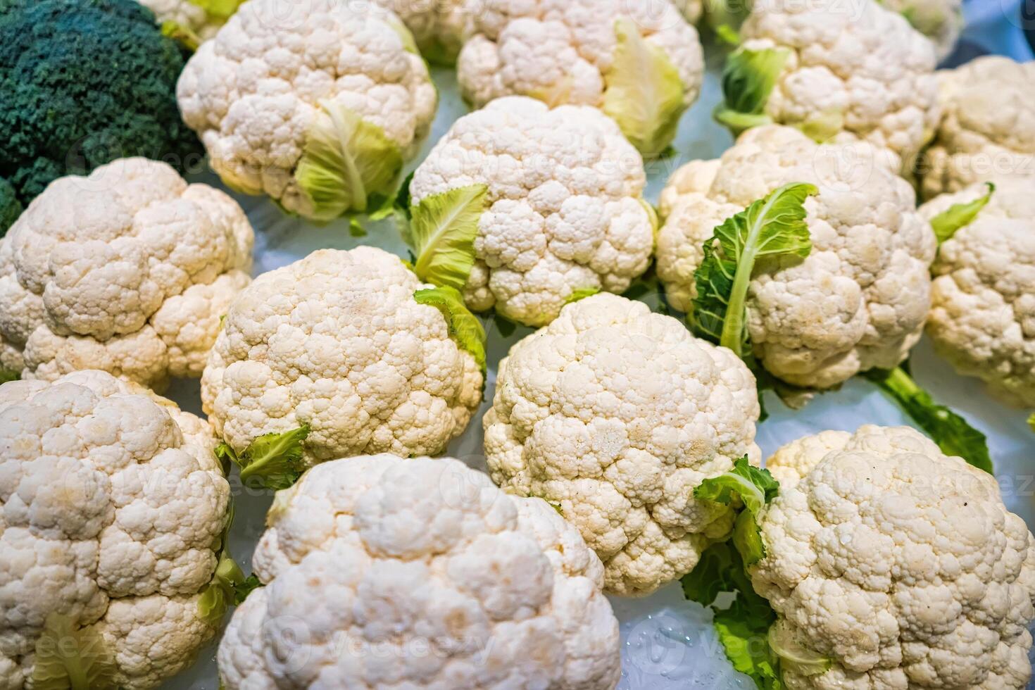 Fresh Organic Cauliflower Heads on Ice Display at Market, Ideal for Healthy Cooking and Rich in Nutrients photo