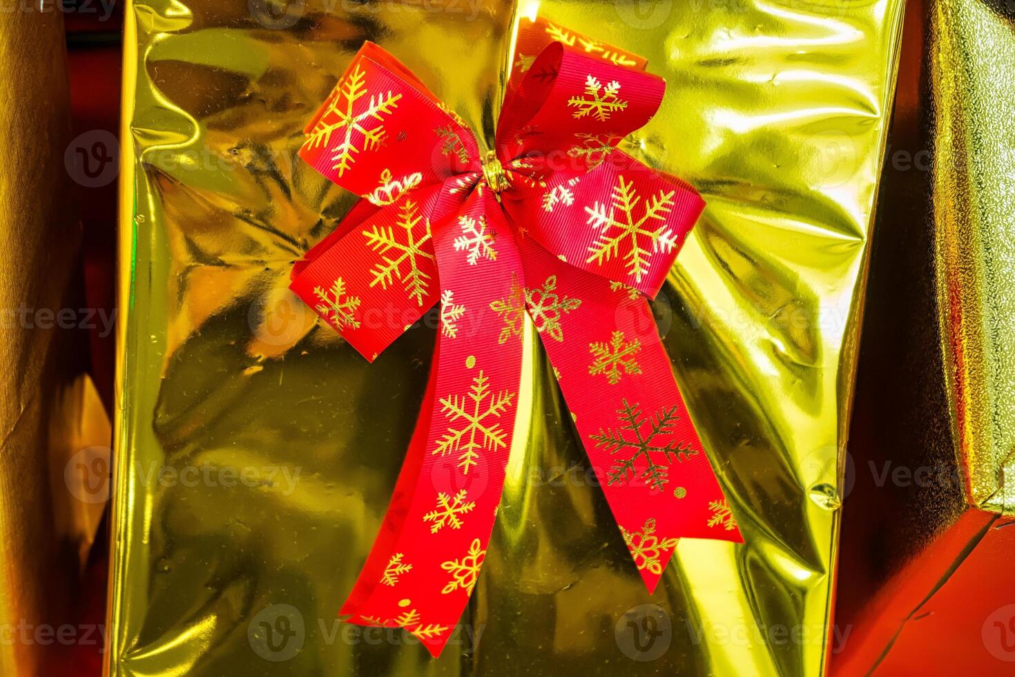 Festive Gift Box Adorned with a Red Ribbon and Gold Wrapping Paper, Radiating Holiday Spirit photo