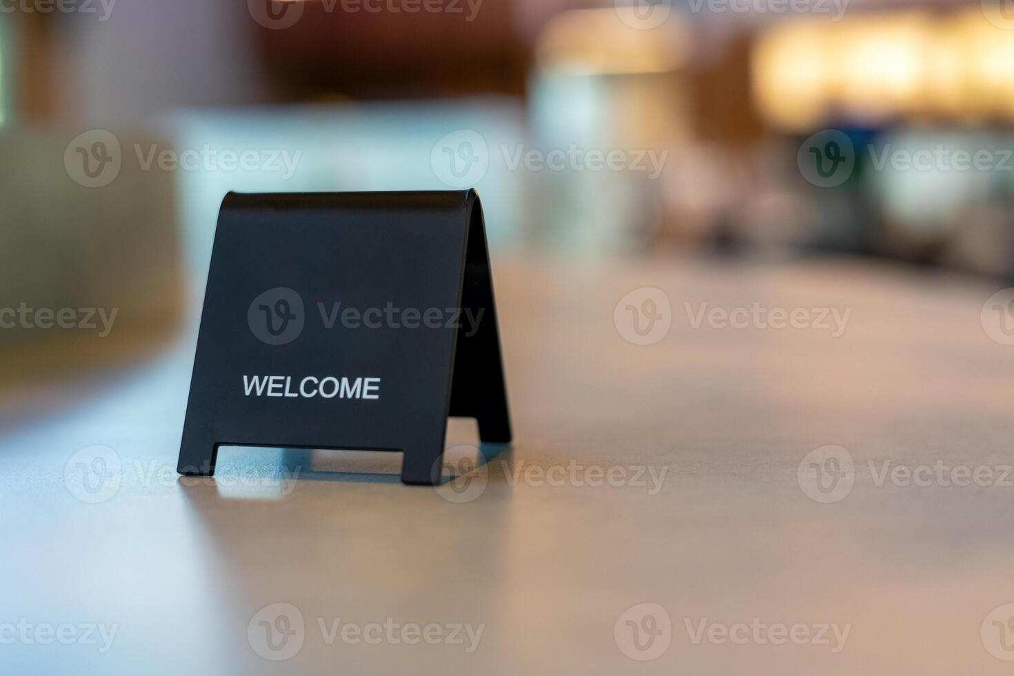 Black sign there is a message saying Welcome with a copy space is placed on a cement table for Enter the text of restaurant, store, or cafe. photo