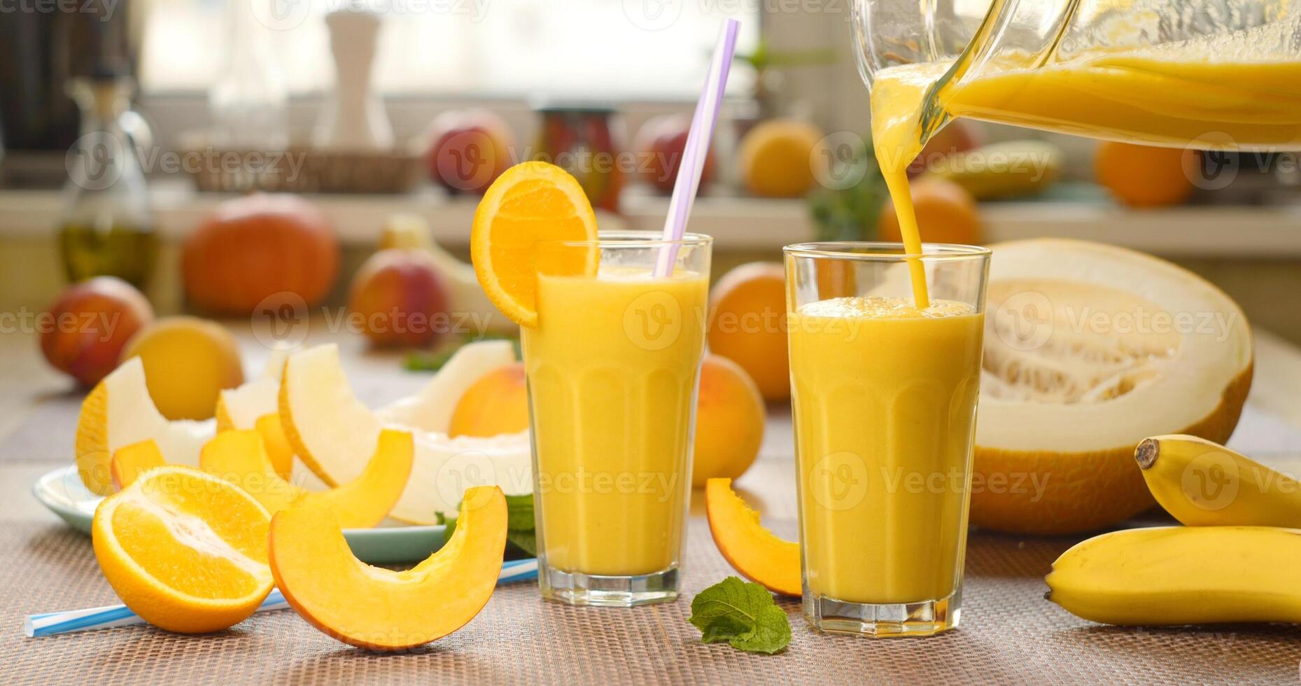 Melon banana Smoothie is poured into a glass on the background of fresh fruits. The fruit cocktail is ready to eat. Healthy and vegetarian food concept. photo