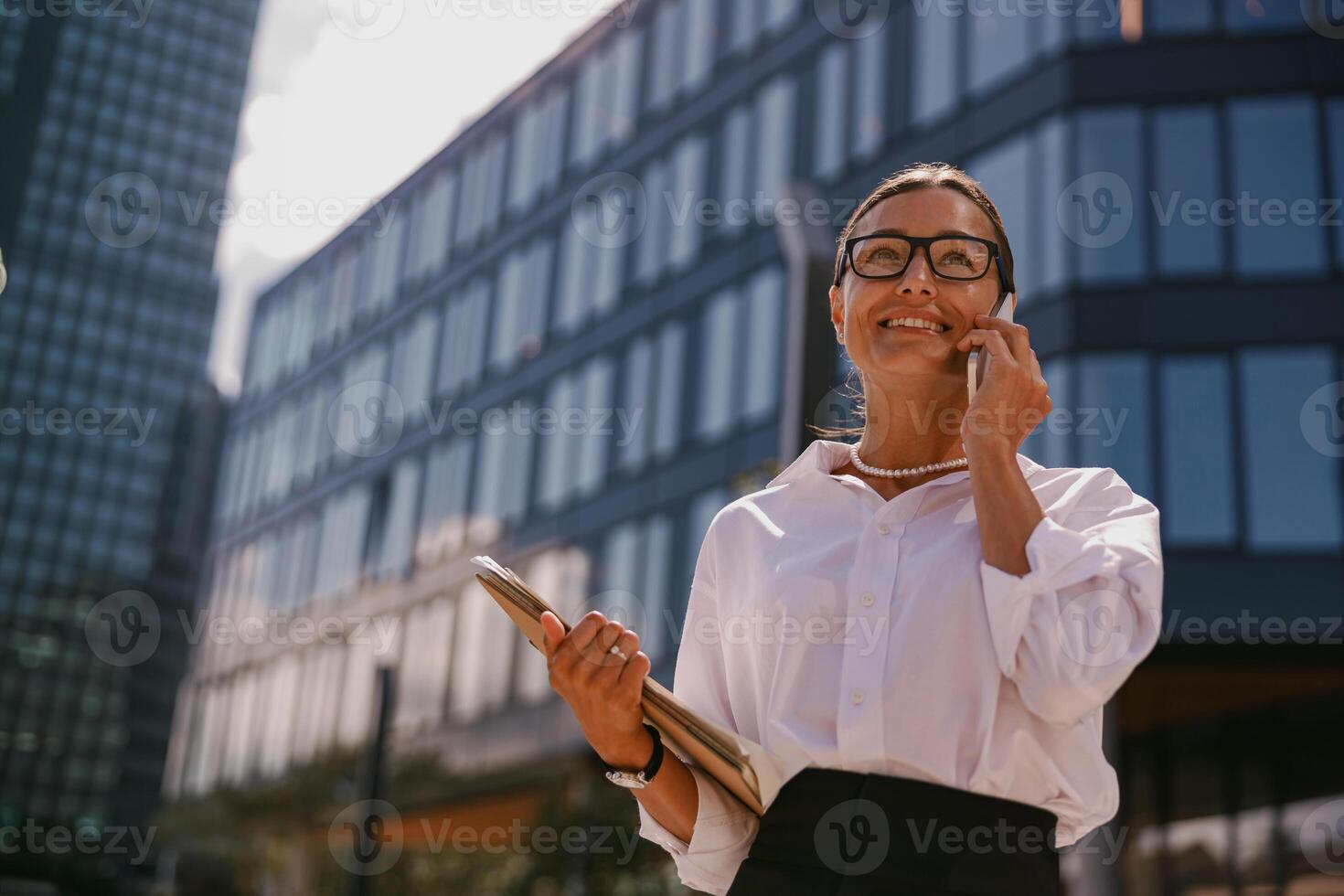 A professional woman dressed in business attire is engaged in a conversation on her phone photo