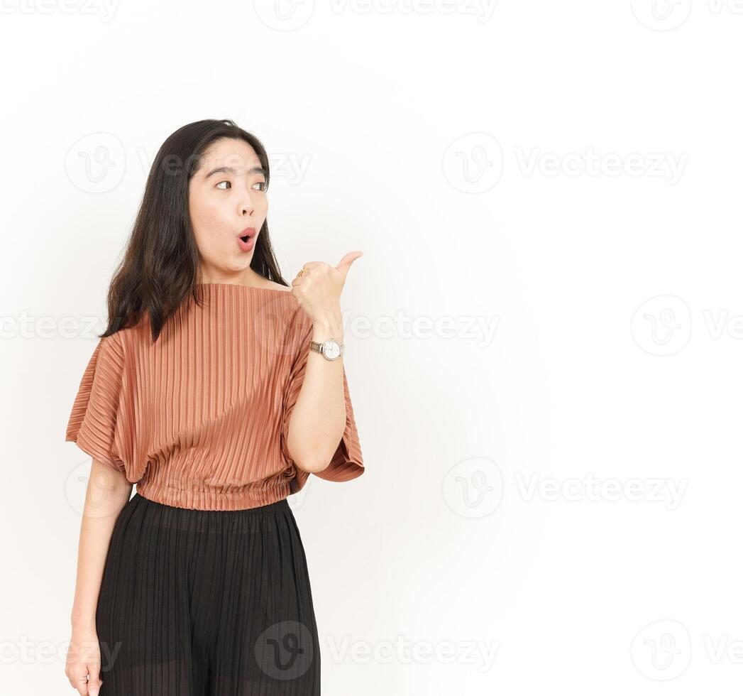 Presenting and Pointing Side Product Using Thumb Of Beautiful Asian Woman Isolated On White Background photo