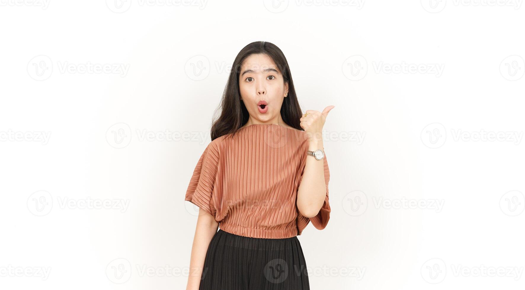 Showing and Pointing Product With Thumb Of Beautiful Asian Woman Isolated On White Background photo