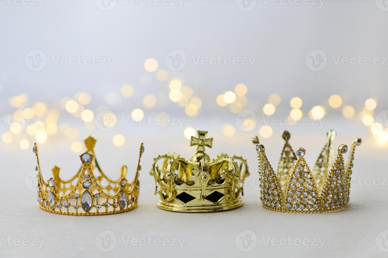 Epiphany Day or Dia de Reyes Magos concept. Three gold crowns on light sparkling background photo