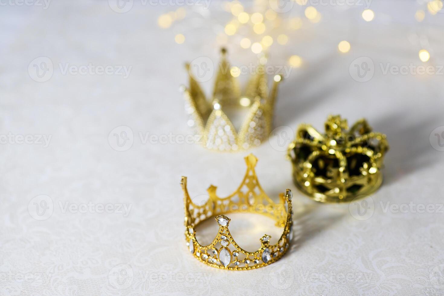 Epiphany Day or Dia de Reyes Magos concept. Three gold crowns on light sparkling background photo