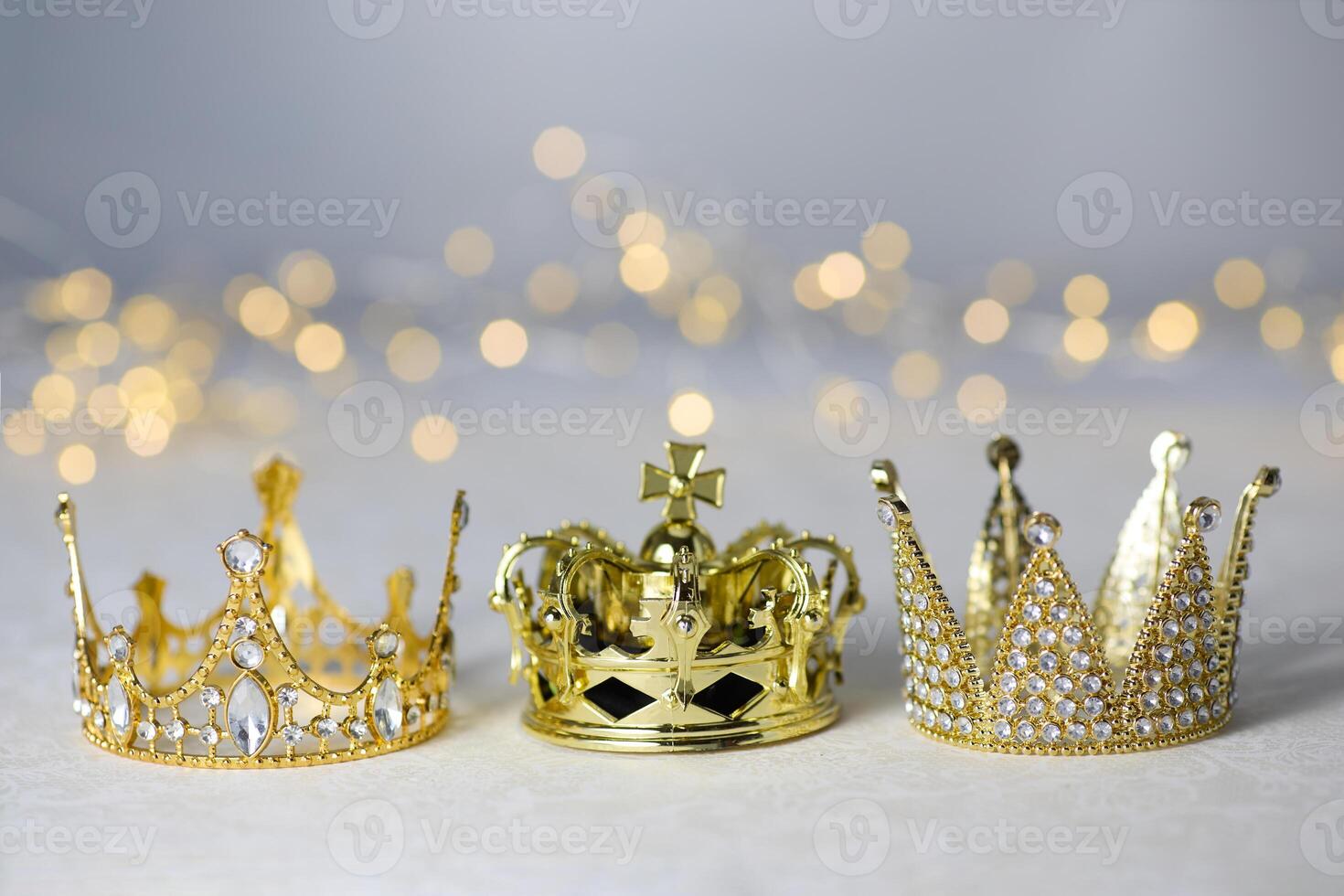 Epiphany Day or Dia de Reyes Magos concept. Three gold crowns on light sparkling background photo