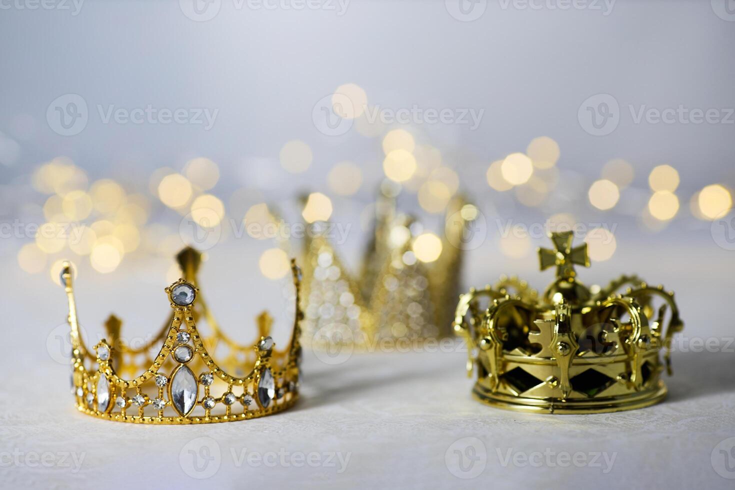 Epiphany Day or Dia de Reyes Magos concept. Three gold crowns on light sparkling background photo