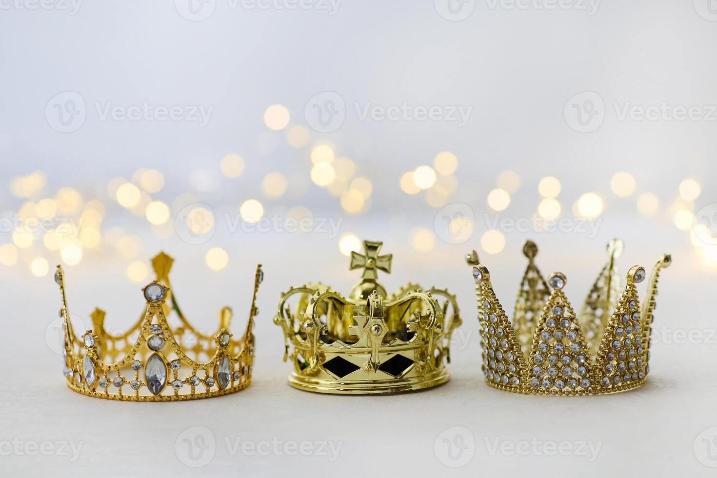 Epiphany Day or Dia de Reyes Magos concept. Three gold crowns on light sparkling background photo