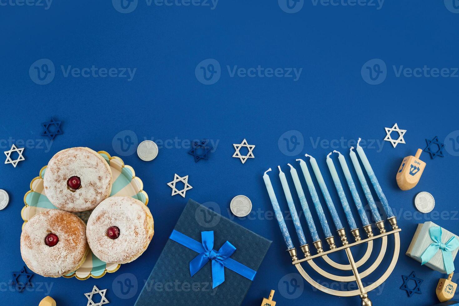 Jewish holiday Hanukkah concept. Frame of traditional jelly donuts and menorah on dark blue background photo