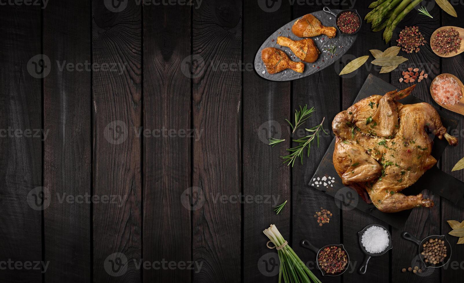 Whole fried chicken with spices on wooden board, brown wooden background photo