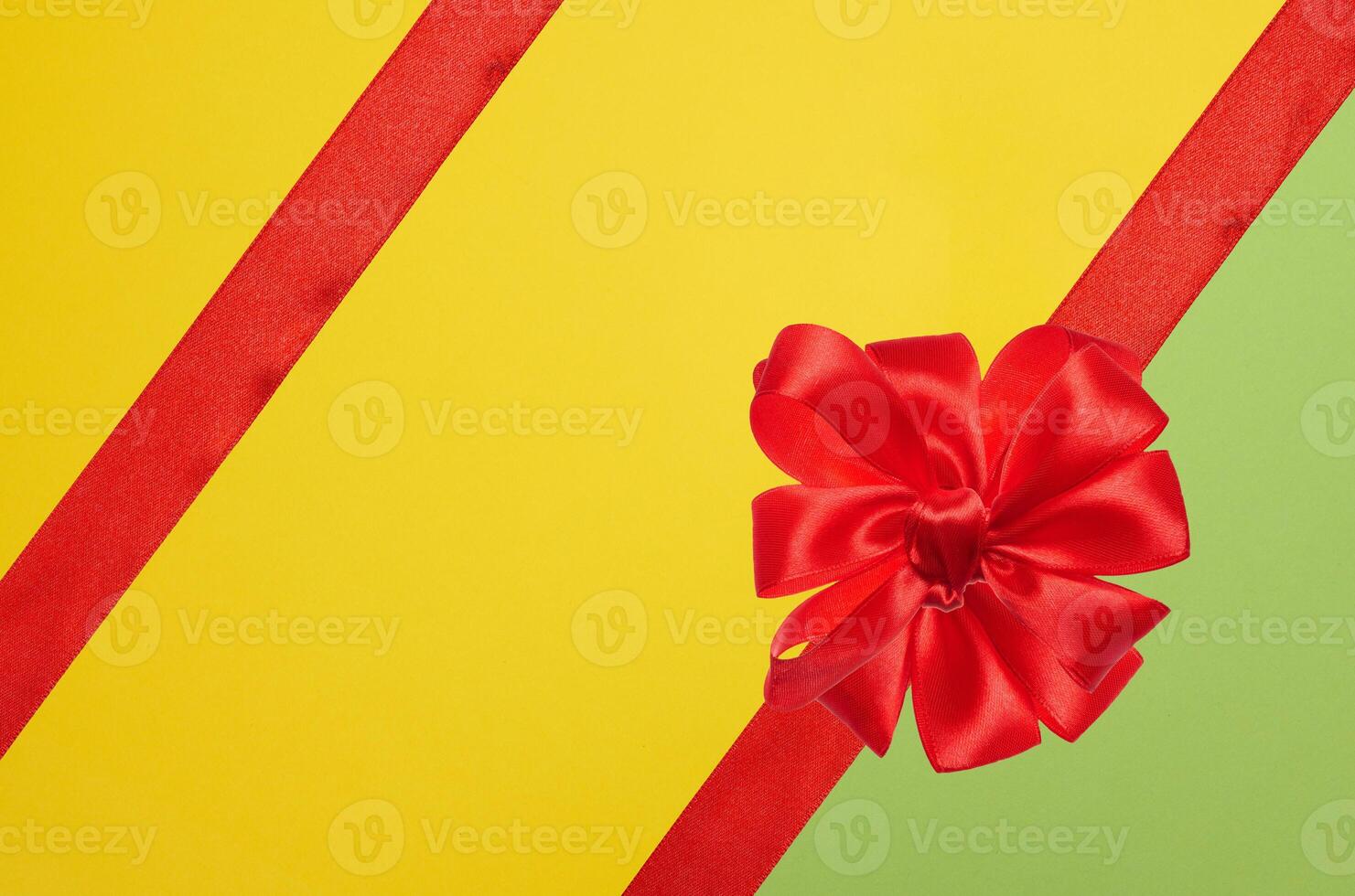 Tied bow made of red silk ribbon on green yellow background, decor for a gift photo
